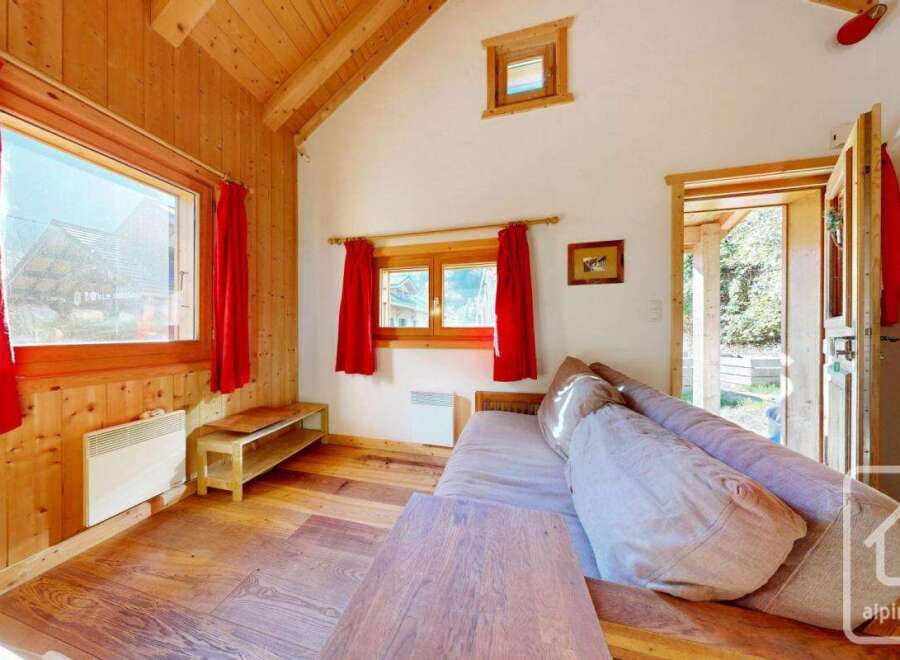 Cozy chalet living room with wood-paneled walls, large windows offering scenic views, and a comfortable sofa for relaxation.