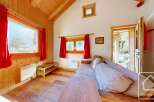 Cozy chalet living room with wood-paneled walls, large windows offering scenic views, and a comfortable sofa for relaxation.