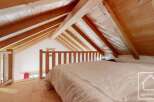 Cosy attic bedroom with wooden beams and a mezzanine level, offering a unique and charming atmosphere.