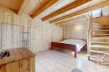This charming wooden chalet bedroom features a double bed, built-in wooden shelving, and a wooden staircase leading to an upper level.