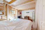 Cosy chalet bedroom with wooden walls and ceiling, featuring a double bed and built-in bunk beds.