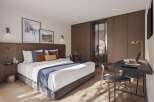 This stunning hotel room boasts a king-size bed with plush bedding, a spacious work desk with a laptop, and large windows that let in plenty of natural light.
