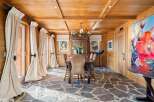 This stunning dining room boasts a rustic-chic design with a wood-paneled ceiling, stone flooring, and large windows that let in plenty of natural light.