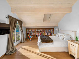 This luxurious bedroom boasts a stunning wooden ceiling, large windows offering scenic views, and ample built-in bookshelves.