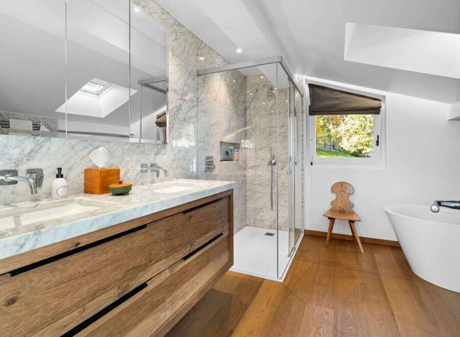 Luxurious bathroom with marble finishes and wooden vanity, featuring a spacious shower and a freestanding bathtub.