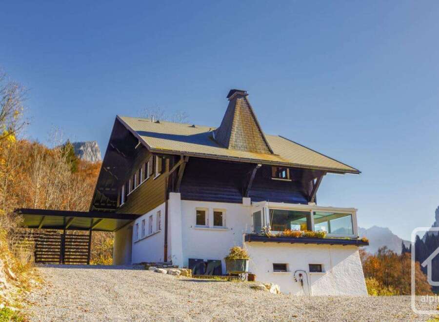 This stunning chalet boasts a unique architectural design, featuring a striking angular roofline and expansive windows offering breathtaking mountain views.