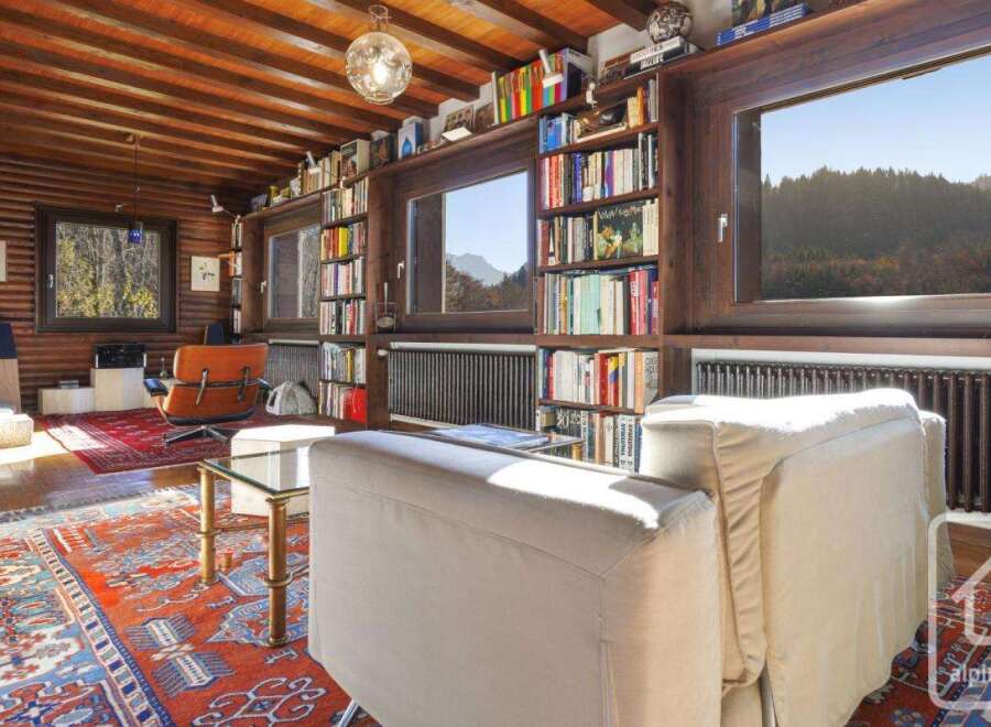This stunning log cabin boasts a spacious living area with floor-to-ceiling windows offering breathtaking mountain views.
