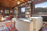 This stunning log cabin boasts a spacious living area with floor-to-ceiling windows offering breathtaking mountain views.