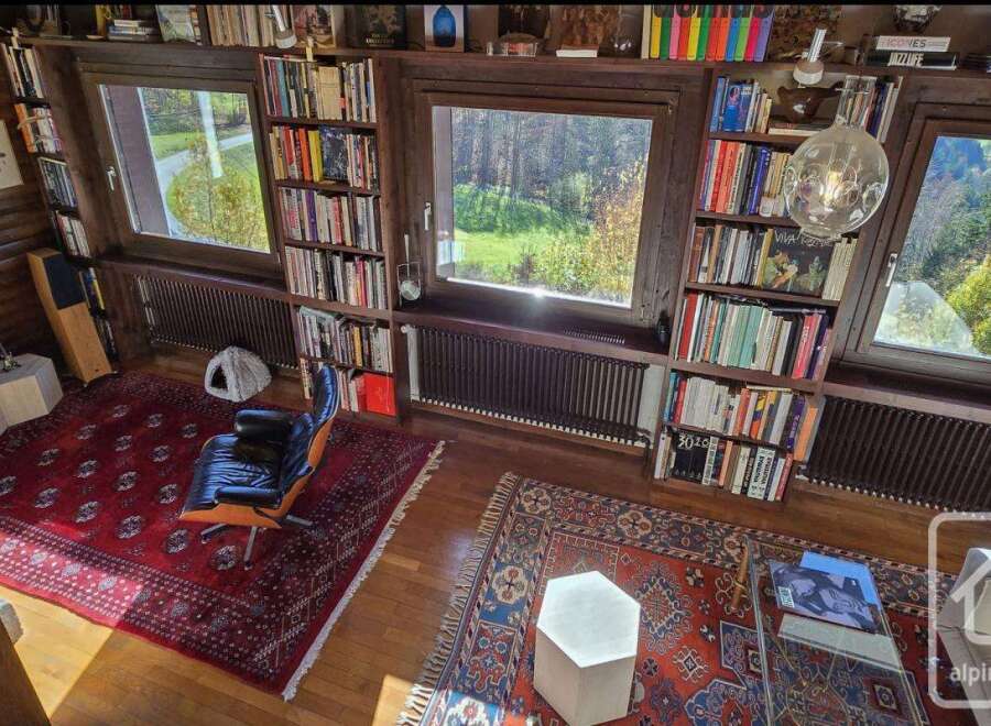 This stunning log cabin boasts a spacious library with floor-to-ceiling bookshelves, large windows offering breathtaking views, and a cozy reading nook.
