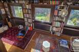 This stunning log cabin boasts a spacious library with floor-to-ceiling bookshelves, large windows offering breathtaking views, and a cozy reading nook.