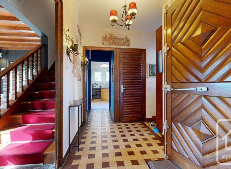 This stunning property boasts a grand entrance with a unique wooden door, leading to a spacious hallway with checkered flooring.