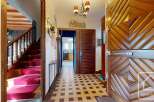 This stunning property boasts a grand entrance with a unique wooden door, leading to a spacious hallway with checkered flooring.