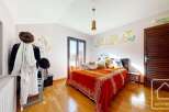 Charming bedroom with wooden floors, a large window offering mountain views, and a cozy bed with an orange blanket.