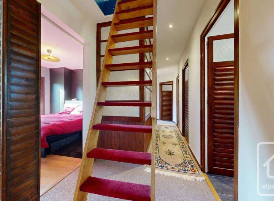 This charming property boasts a unique wooden staircase with red carpeting, adding a touch of elegance to the hallway.