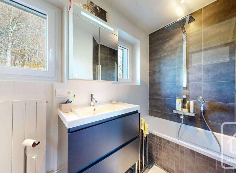 This modern bathroom boasts a sleek, dark-grey vanity with ample storage, complemented by a clean white sink and countertop.