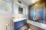 This modern bathroom boasts a sleek, dark-grey vanity with ample storage, complemented by a clean white sink and countertop.