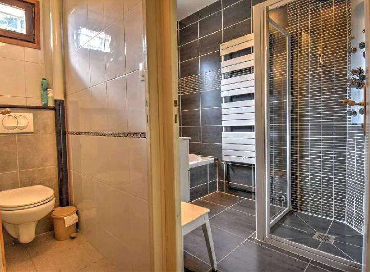 This charming property boasts a modern bathroom with a walk-in shower and a wall-mounted toilet.