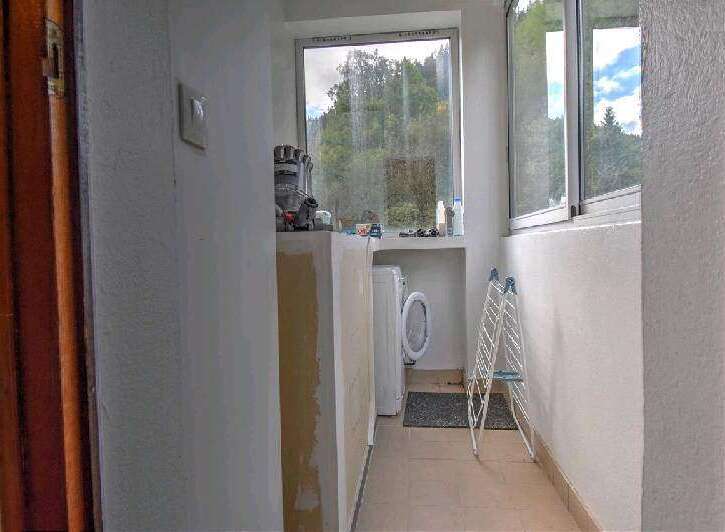 This property boasts a convenient laundry area with a washing machine, located in a sunlit space with a window offering scenic views.
