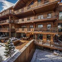 This stunning chalet boasts multiple levels of expansive wooden balconies, offering breathtaking views of the snowy landscape.