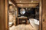 This luxurious bathroom boasts a stunning combination of rustic wood paneling and sleek black marble tiles, creating a warm and sophisticated ambiance.