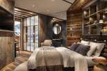 This luxurious hotel room boasts a stunning mountain view from its large windows and features a cozy, rustic design with wood paneling and a comfortable king-size bed.