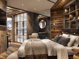 This luxurious hotel room boasts a stunning mountain view from its large windows and features a cozy, rustic design with wood paneling and a comfortable king-size bed.