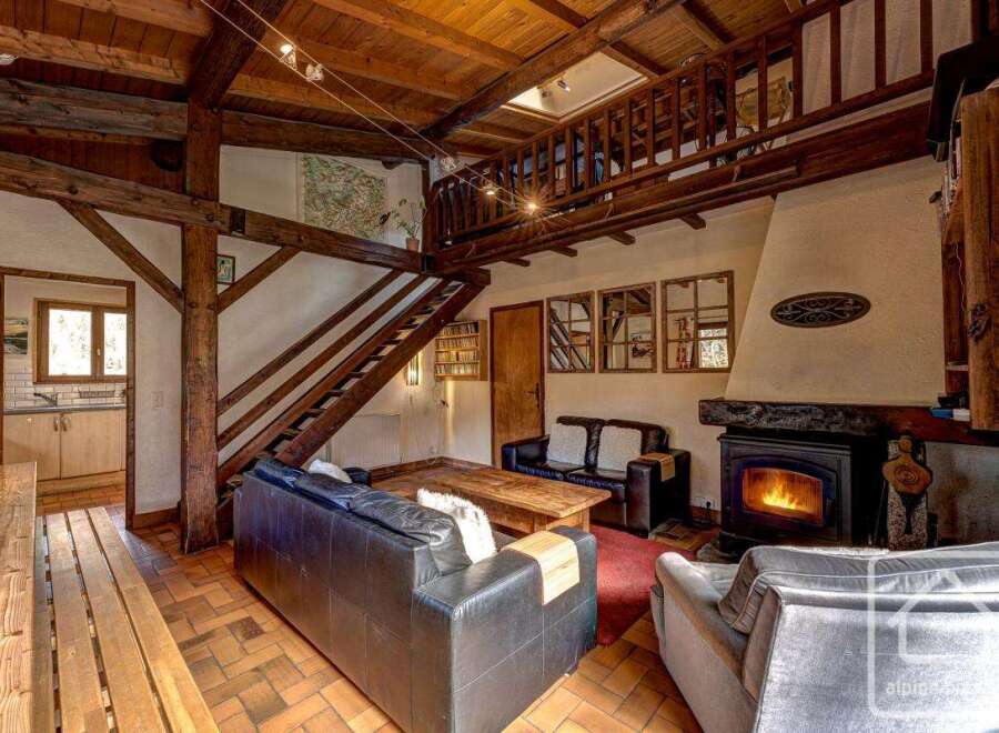 This charming chalet boasts a spacious living area with exposed wooden beams, a cozy fireplace, and comfortable leather sofas.