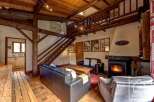 This charming chalet boasts a spacious living area with exposed wooden beams, a cozy fireplace, and comfortable leather sofas.