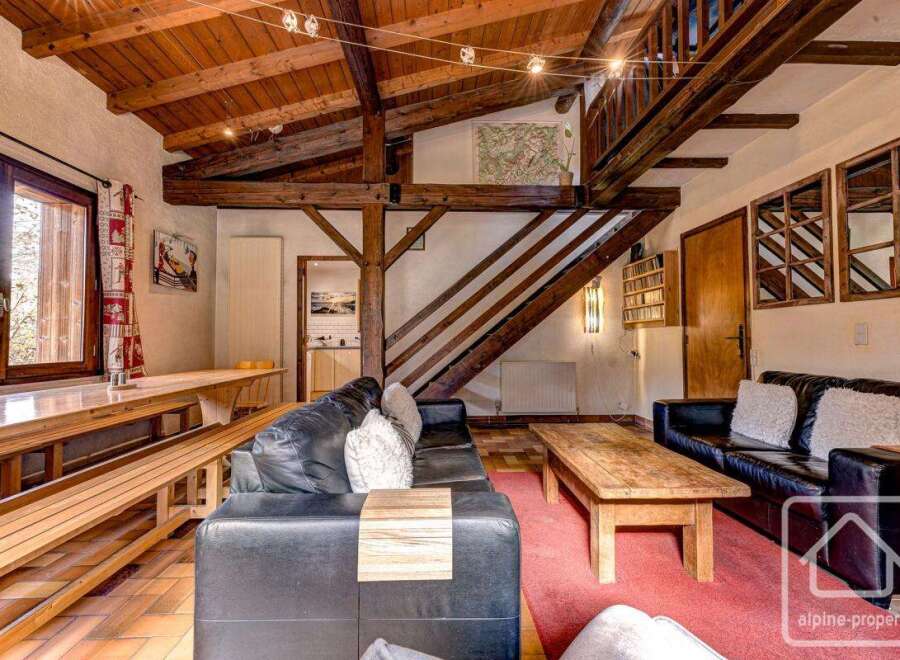 This charming chalet boasts a spacious open-plan living area with exposed wooden beams, creating a warm and inviting atmosphere.