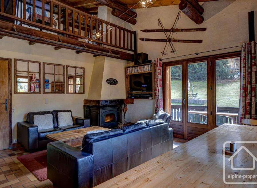This charming chalet boasts a spacious living area with comfortable leather sofas, a cozy fireplace, and large windows offering stunning views of the surrounding landscape.