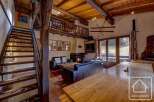 This charming chalet boasts a spacious open-plan living area with exposed wooden beams, a cozy fireplace, and large windows offering stunning views.