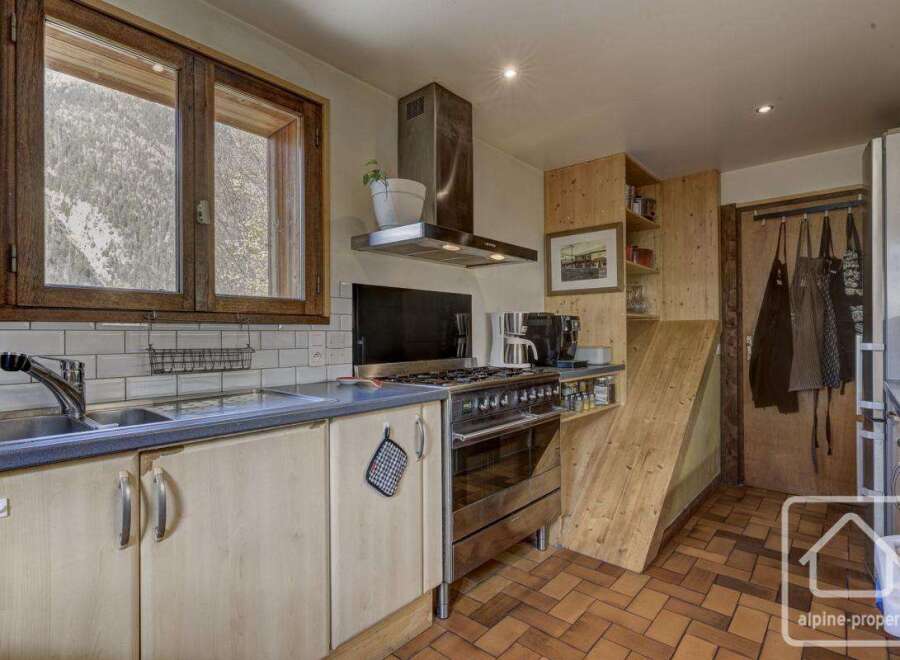 This charming kitchen boasts a rustic-chic design with light wood cabinets, white subway tile backsplash, and a large window offering stunning mountain views.