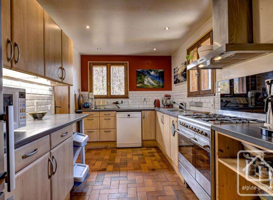 This charming kitchen boasts a rustic-chic design with light wood cabinetry, terracotta tile flooring, and stainless steel appliances.