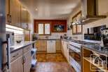This charming kitchen boasts a rustic-chic design with light wood cabinetry, terracotta tile flooring, and stainless steel appliances.