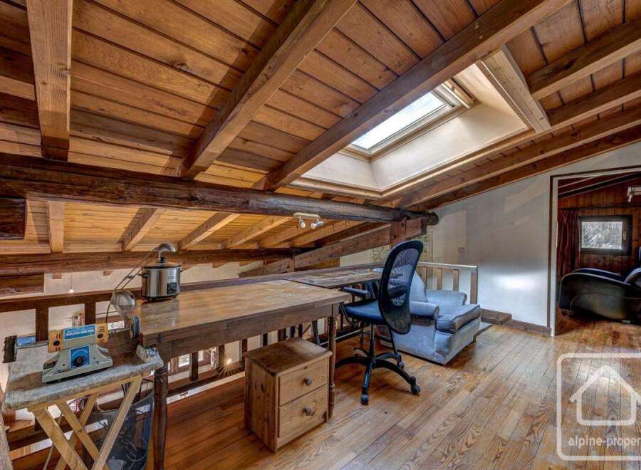 Discover this unique chalet featuring a charming attic workspace with exposed wooden beams and skylights, creating a bright and inspiring atmosphere.