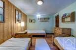 Cozy chalet bedroom with three single beds, wooden walls, and ample storage.