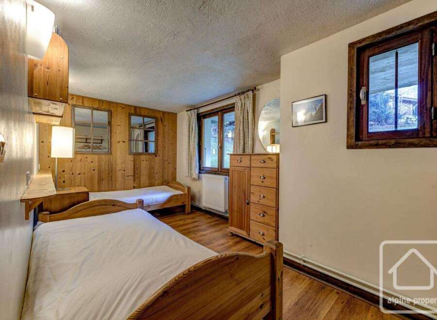 Cozy chalet bedroom with twin beds, wooden walls, and large windows offering scenic views.