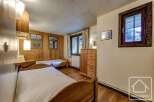 Cozy chalet bedroom with twin beds, wooden walls, and large windows offering scenic views.