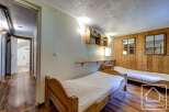 Cozy chalet bedroom with twin beds, wooden walls, and built-in shelves.