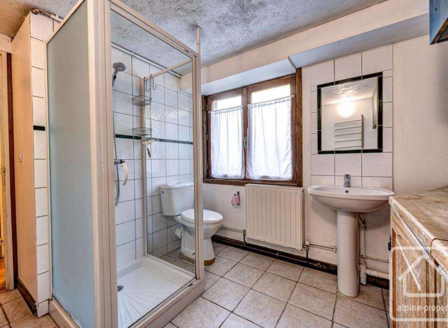 This charming bathroom boasts a spacious shower enclosure, a pedestal sink, and a toilet, all within a bright and airy space.