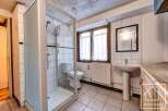 This charming bathroom boasts a spacious shower enclosure, a pedestal sink, and a toilet, all within a bright and airy space.