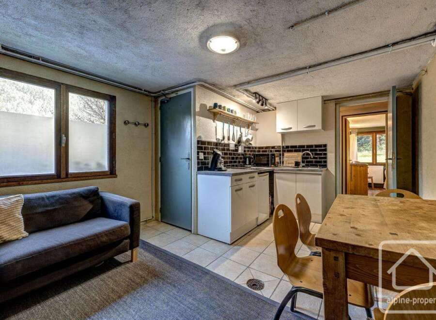 Cozy chalet apartment featuring a well-equipped kitchenette, comfortable living area with sofa, and dining space.