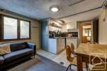 Cozy chalet apartment featuring a well-equipped kitchenette, comfortable living area with sofa, and dining space.