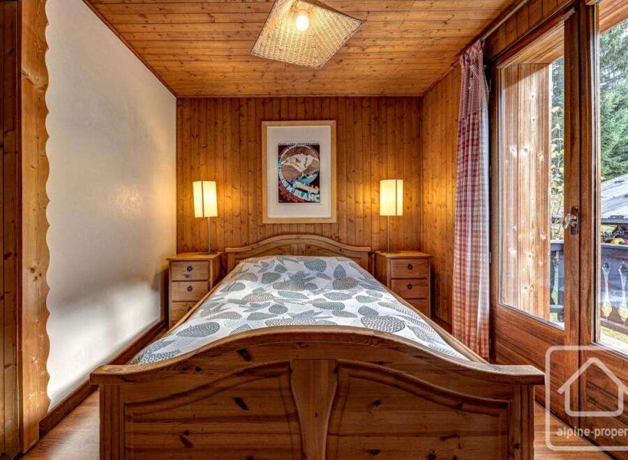 Cozy chalet bedroom with wooden walls and floors, featuring a comfortable double bed and bedside tables.