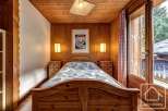 Cozy chalet bedroom with wooden walls and floors, featuring a comfortable double bed and bedside tables.