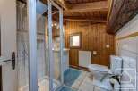 Charming chalet bathroom with rustic wood paneling, a walk-in shower, and a toilet.