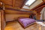 Charming attic bedroom with exposed wooden beams and skylights, offering ample natural light.