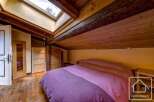 Cosy attic bedroom with wooden beams and skylights, offering a unique and charming atmosphere.
