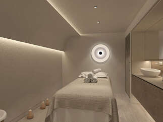 Relax in this serene spa room, featuring a comfortable massage bed with plush towels, ambient lighting, and calming decor.