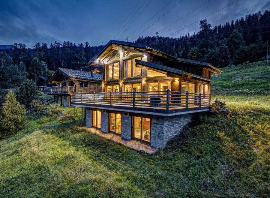Nestled in a serene mountain landscape, this stunning property boasts a modern chalet design with expansive windows that offer breathtaking views.